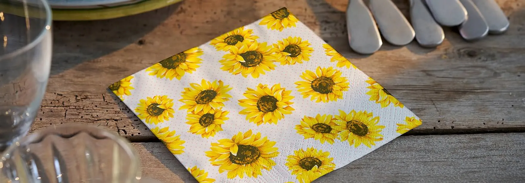 Servietten zum Thema Herbst 2026 Ein weiße Servietten mit kleinen Sonnenblumen liegt auf einem Tisch.